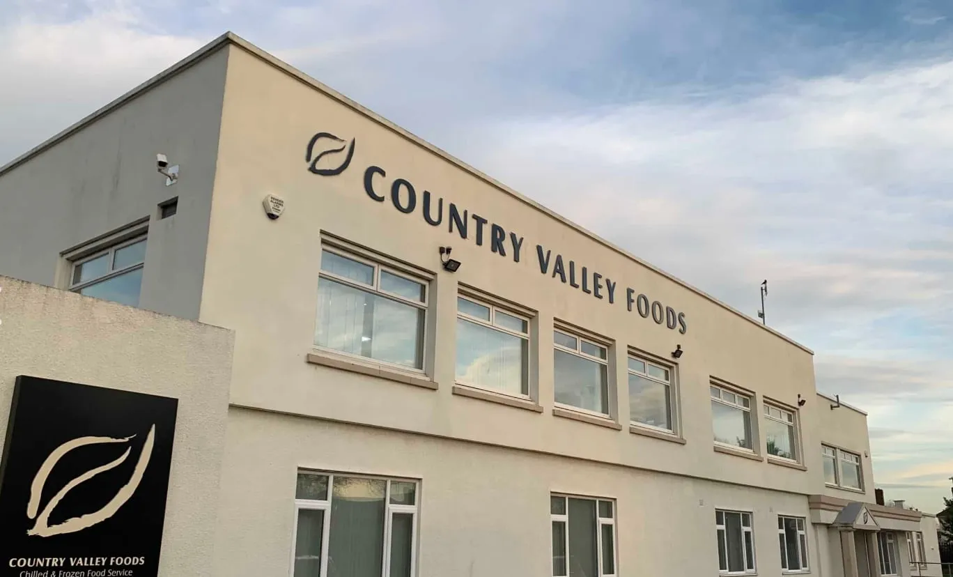 The Country Valley Foods building, cream walls with the company name and leaf logo, and its chilled and frozen food service sign