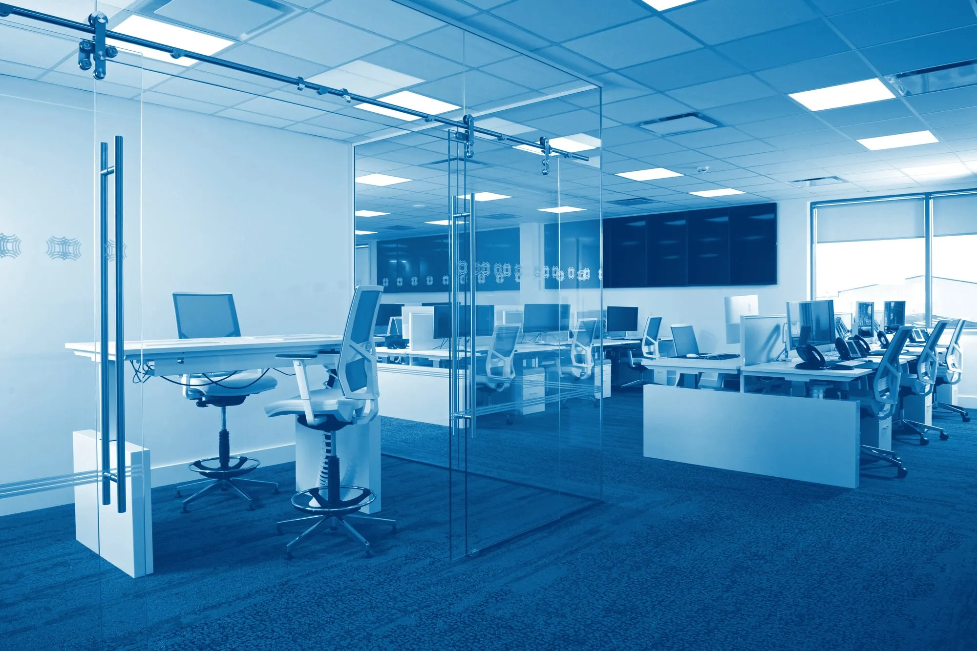 The Odyssey office at Preston Farm: a glass meeting room in front of the service desk and its wall of monitoring screens