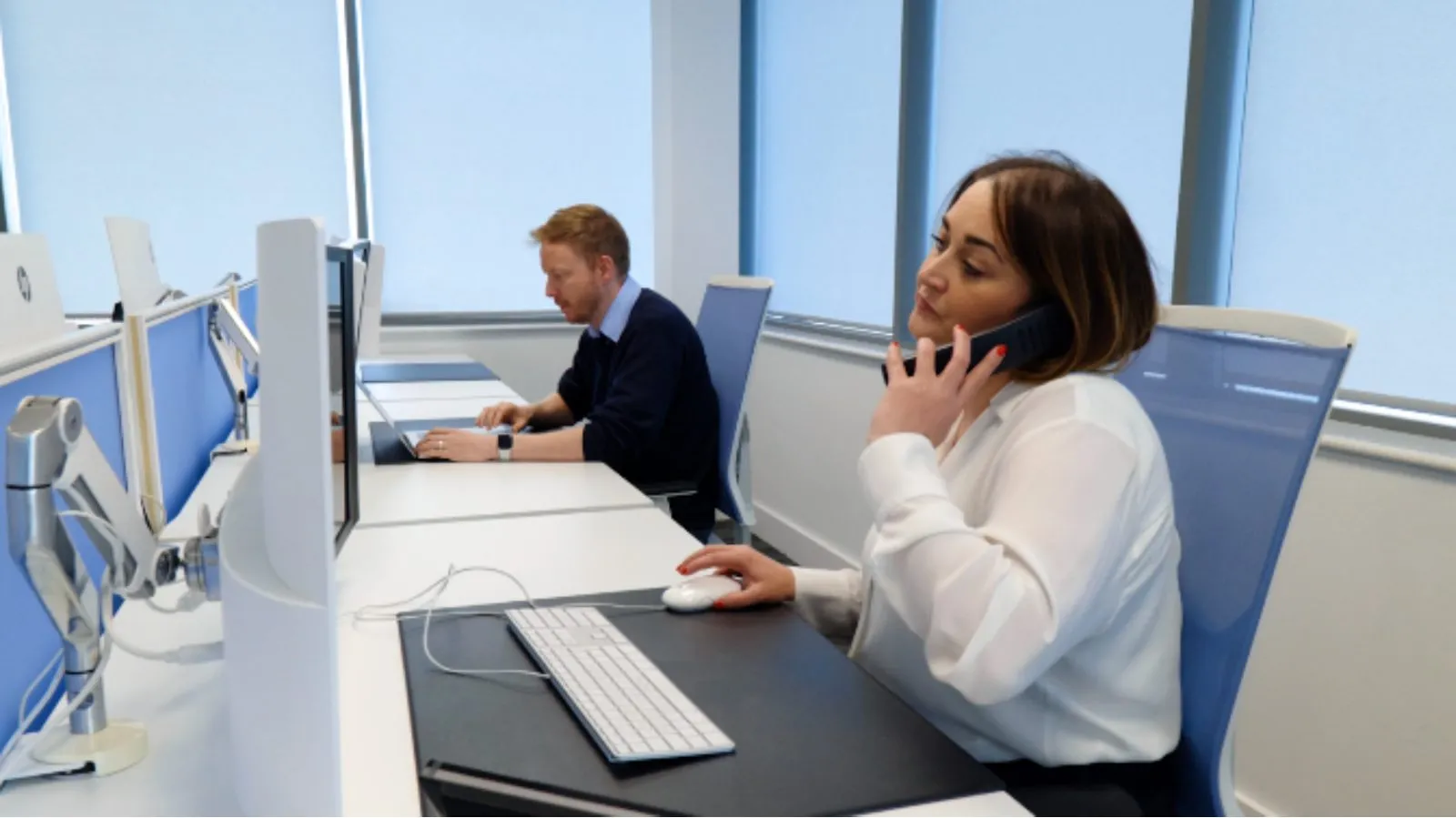 An Odyssey service desk agent taking a call at her desk, with a colleague working behind her