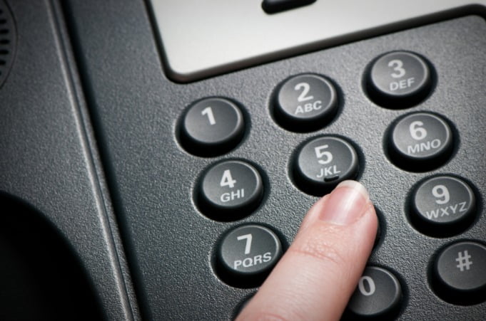 woman pressing a VoIP conference call telephone